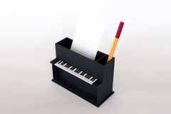 Ein oben geöffnetes schwarzes Klavier aus Pappe für Zettel und Stifte