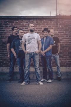 Die Band Eat the Beat steht vor einer Klinkermauer
