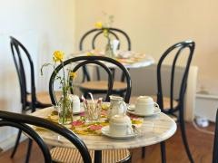 Mehrere Tische sind hübsch hergerichtet. Auf den Tischen stehen Kaffeetassen und Blumen.